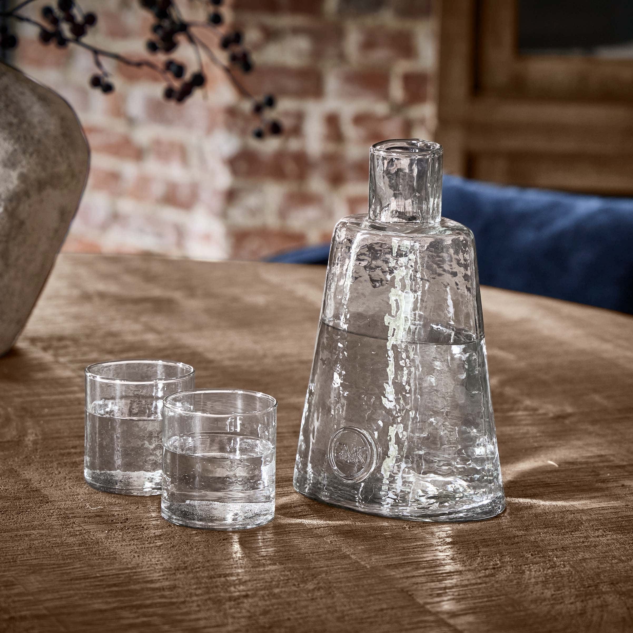Carafe en verre transparent avec deux verres sur une table en bois dans un intérieur rustique