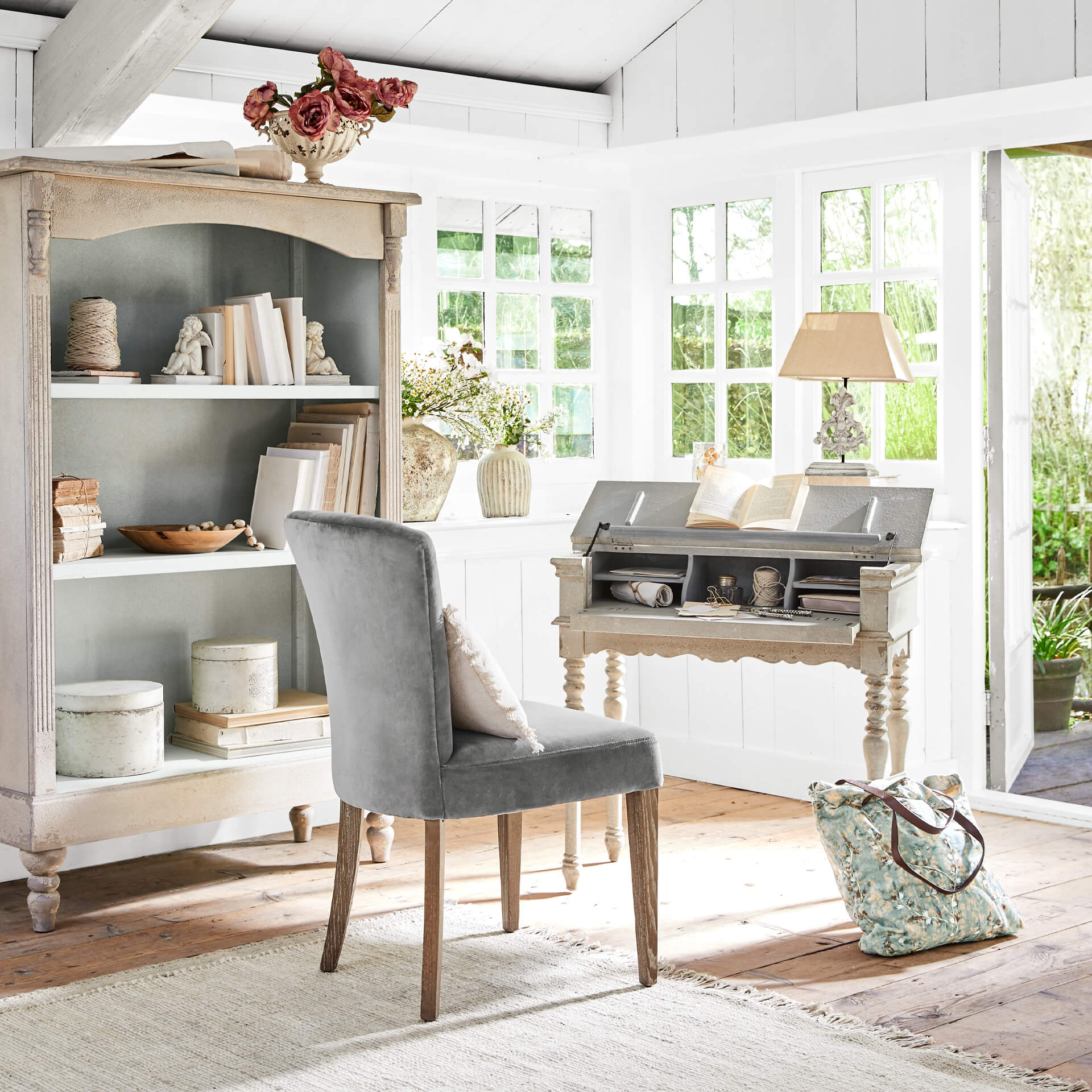 Intérieur lumineux avec chaise en bois grise rembourrée et bureau vintage en bois clair décoré