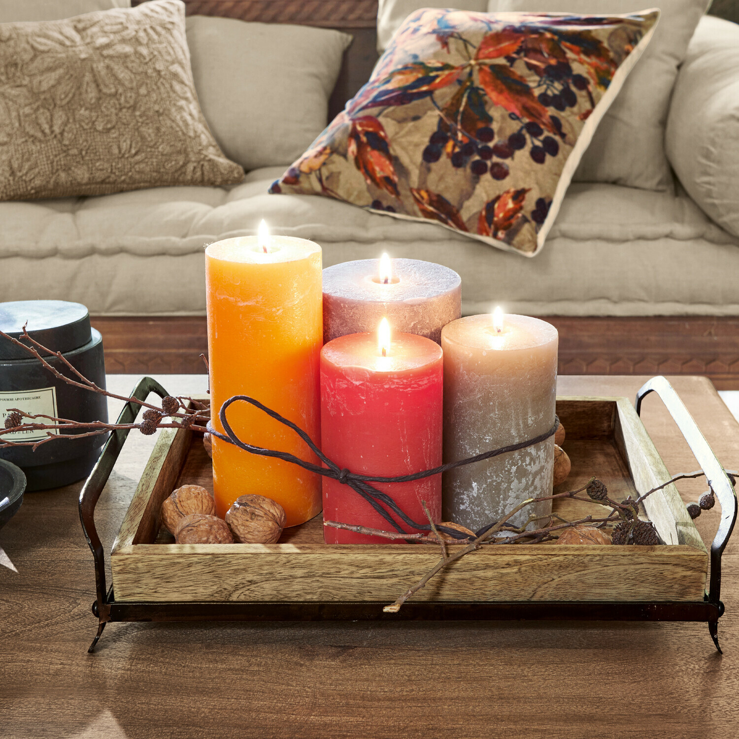 Lot de 4 bougies Joliet Quatre bougies colorées sur un plateau en bois avec poignées métalliques sur une table en bois