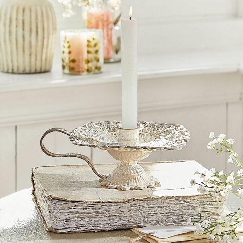 Chandelier en métal crème style vintage posé sur un livre blanc, décoration de table avec fleurs blanches