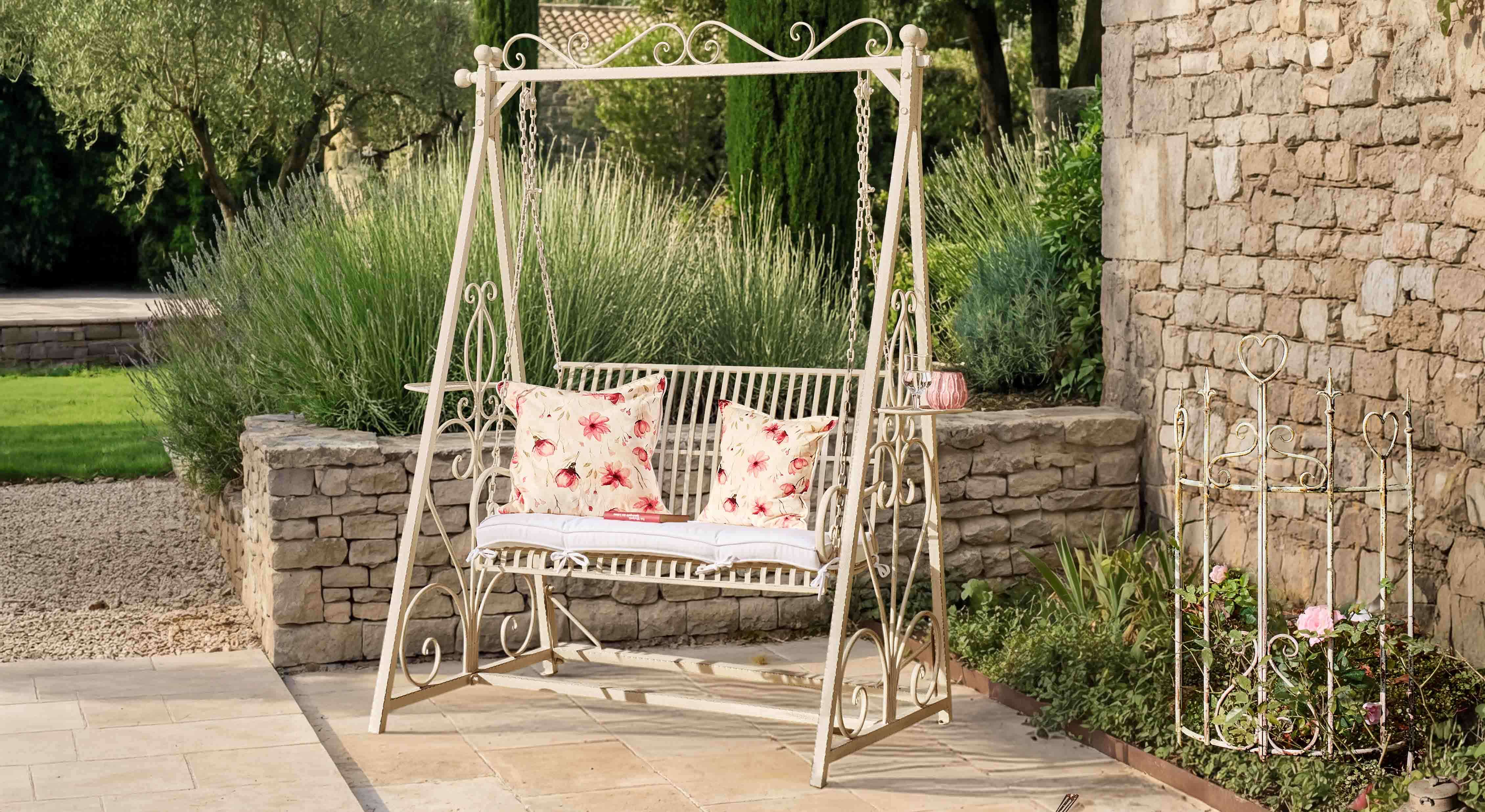 Balançoire de jardin en métal crème avec coussins à motif floral sur terrasse en pierre naturelle