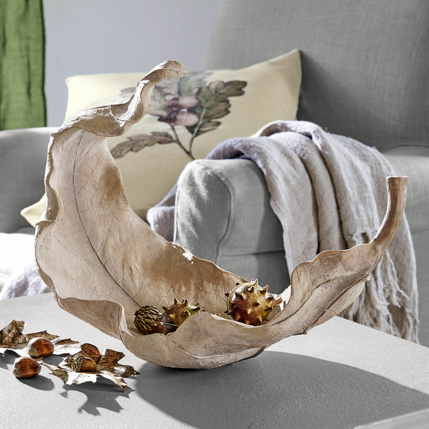 Coupe Vibius Coupe décorative en forme de feuille en matériau naturel beige posée sur une table de salon