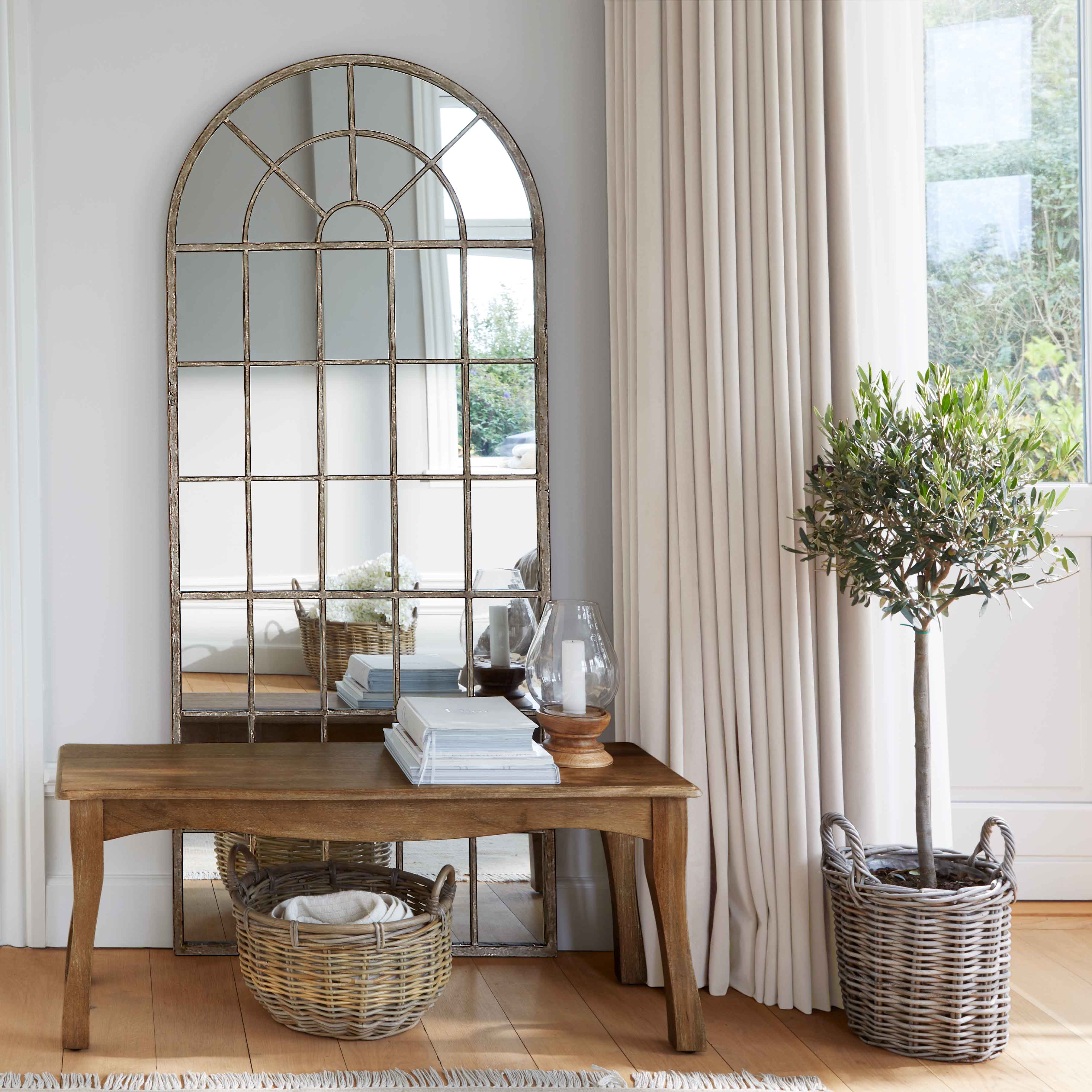 Table en bois avec miroir à cadre métallique et panier en osier dans un intérieur lumineux