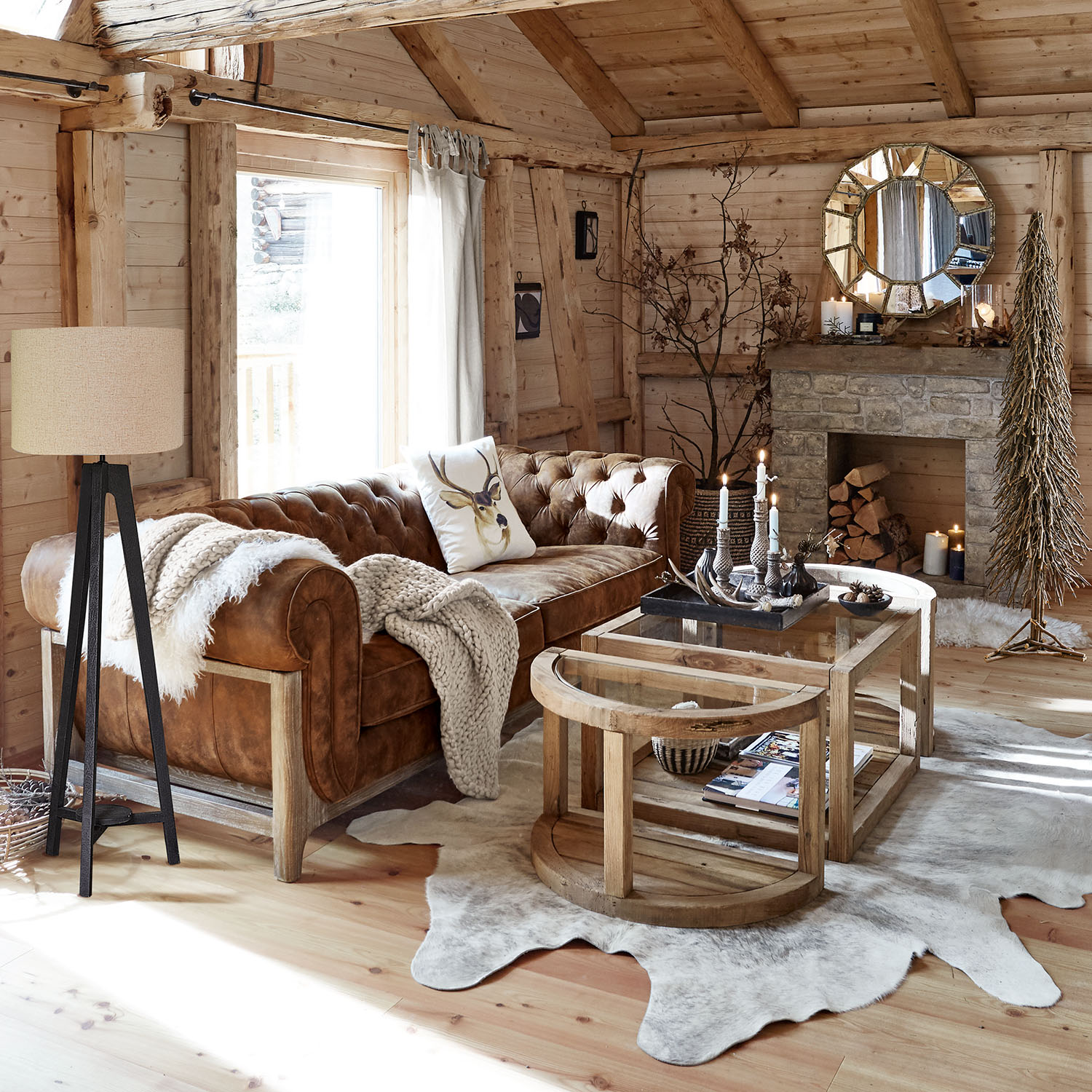 Salon chaleureux avec canapé en cuir marron, tables basses en bois et cheminée en pierre rustique