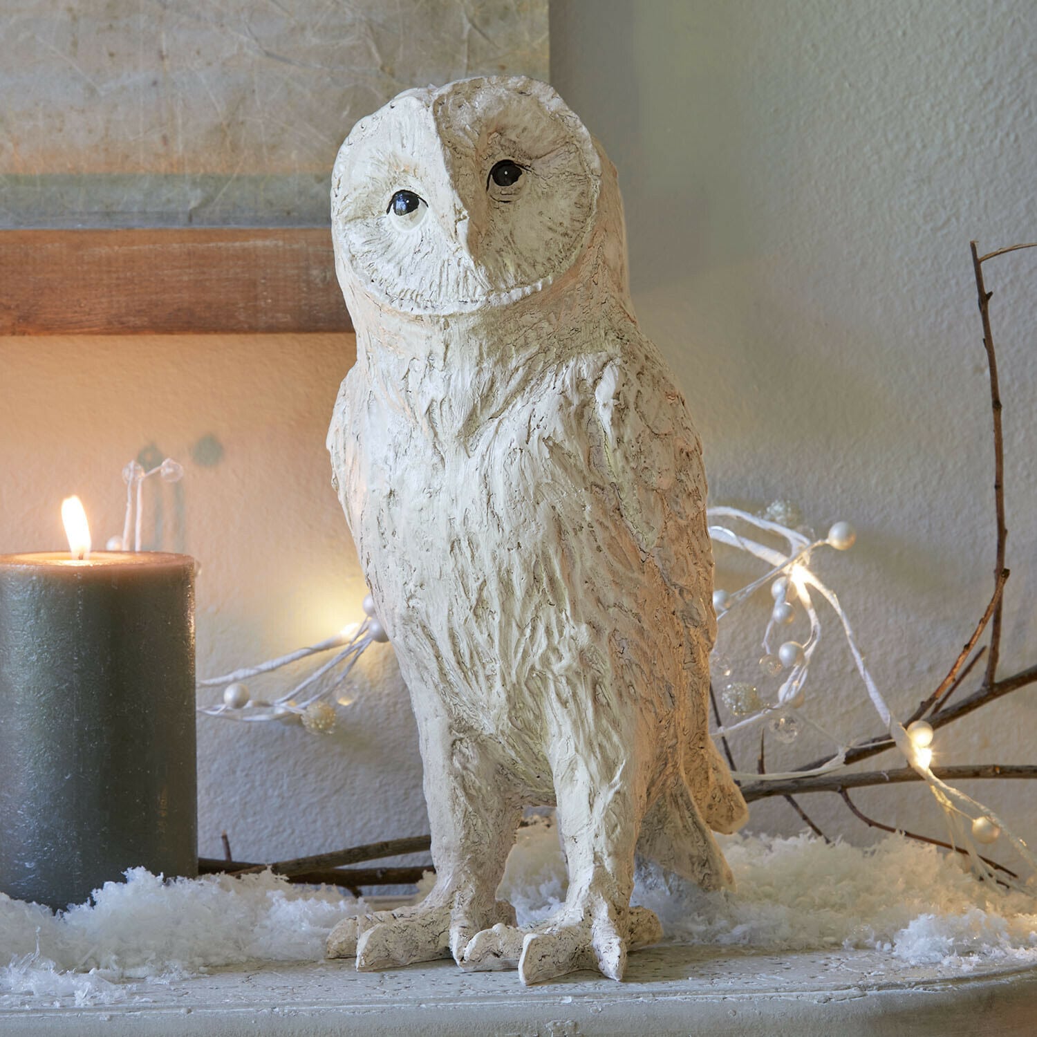 Chouette décorative Heriette Figurine de chouette décorative en matériau clair sur une table festive avec bougie et guirlande lumineuse