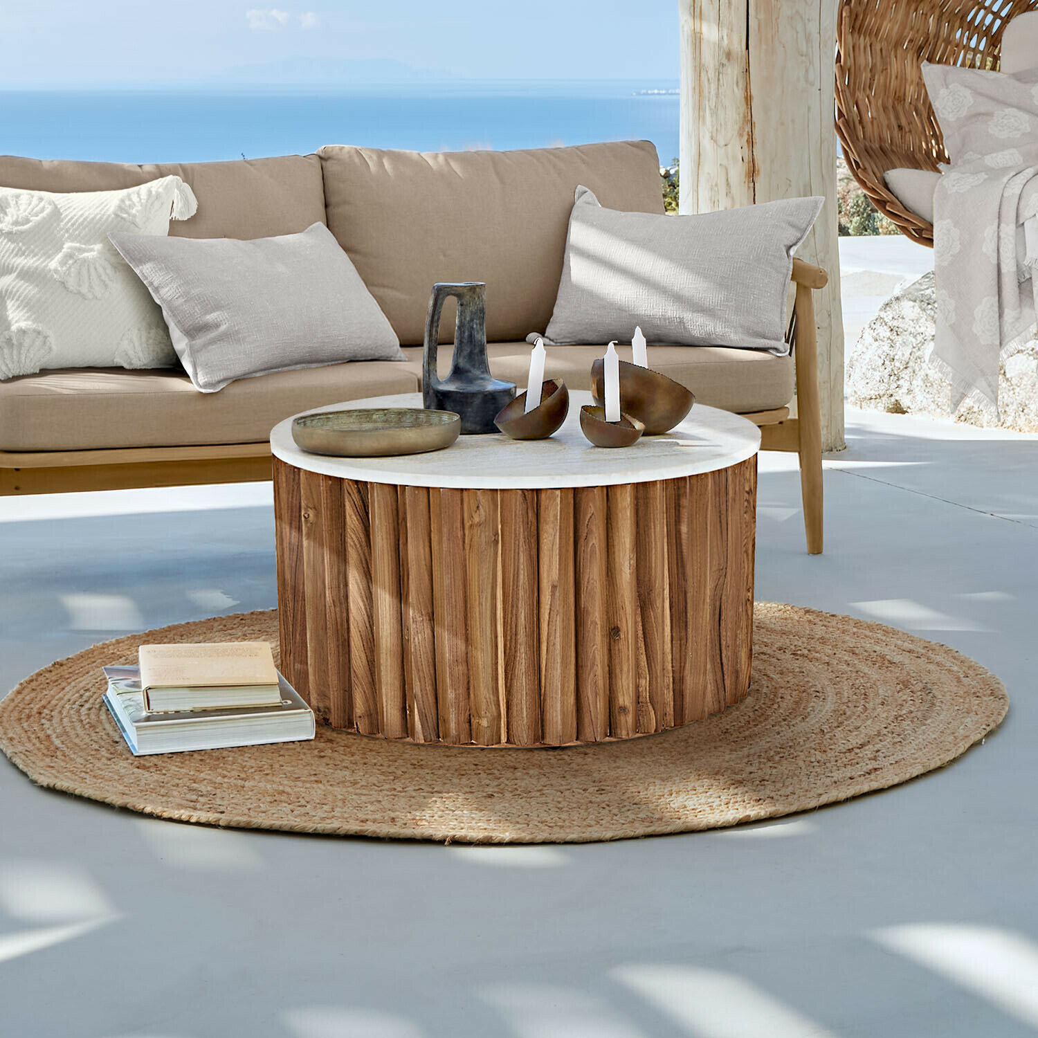 Table basse ronde en bois avec plateau blanc sur tapis rond en jute dans un salon lumineux