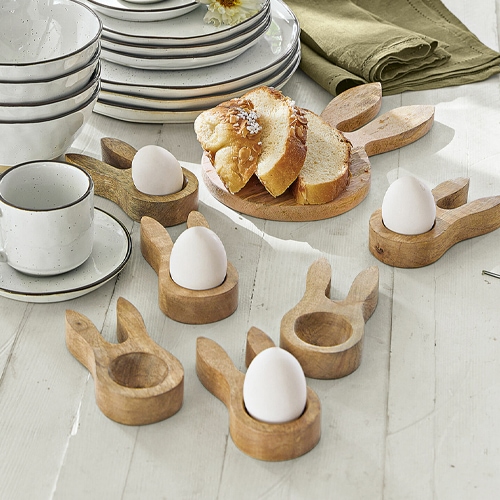 Porte-œufs en bois en forme d'oreilles de lapin sur table blanche avec pain et vaisselle