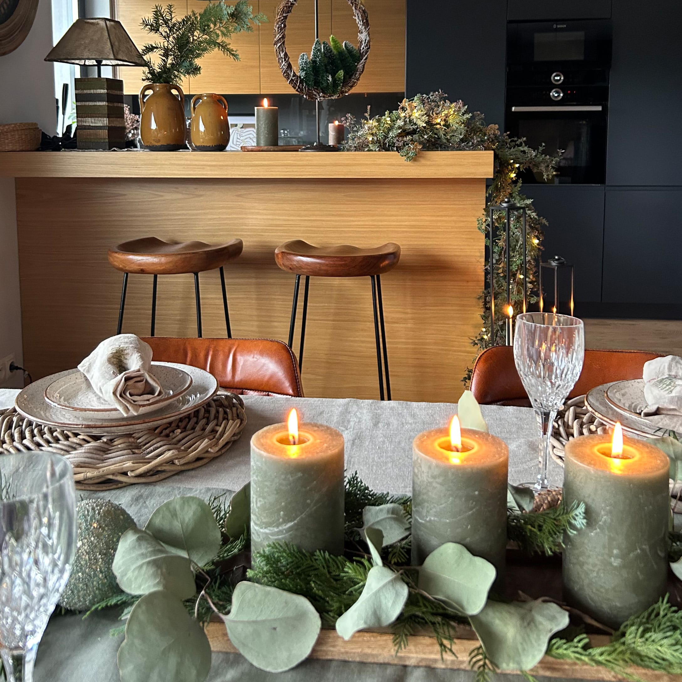 Bougies vertes décoratives avec feuillage naturel sur plateau en bois sur une table à manger élégante