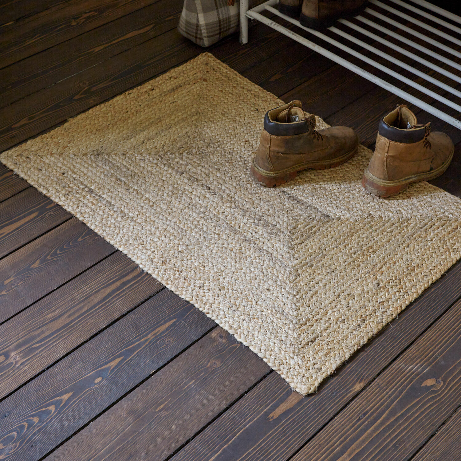 Tapis long Révalaine Tapis beige en jute sur un sol en bois foncé avec une paire de bottes en cuir marron