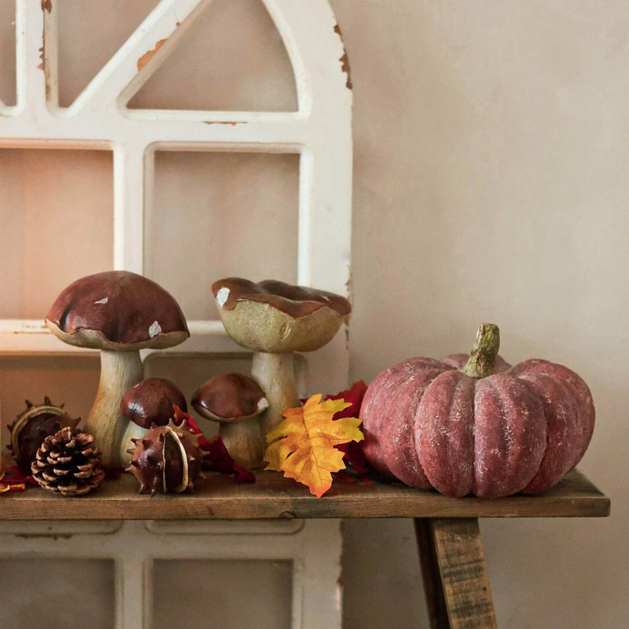 Décoration d'automne avec champignons en céramique et citrouille rose sur une étagère en bois rustique