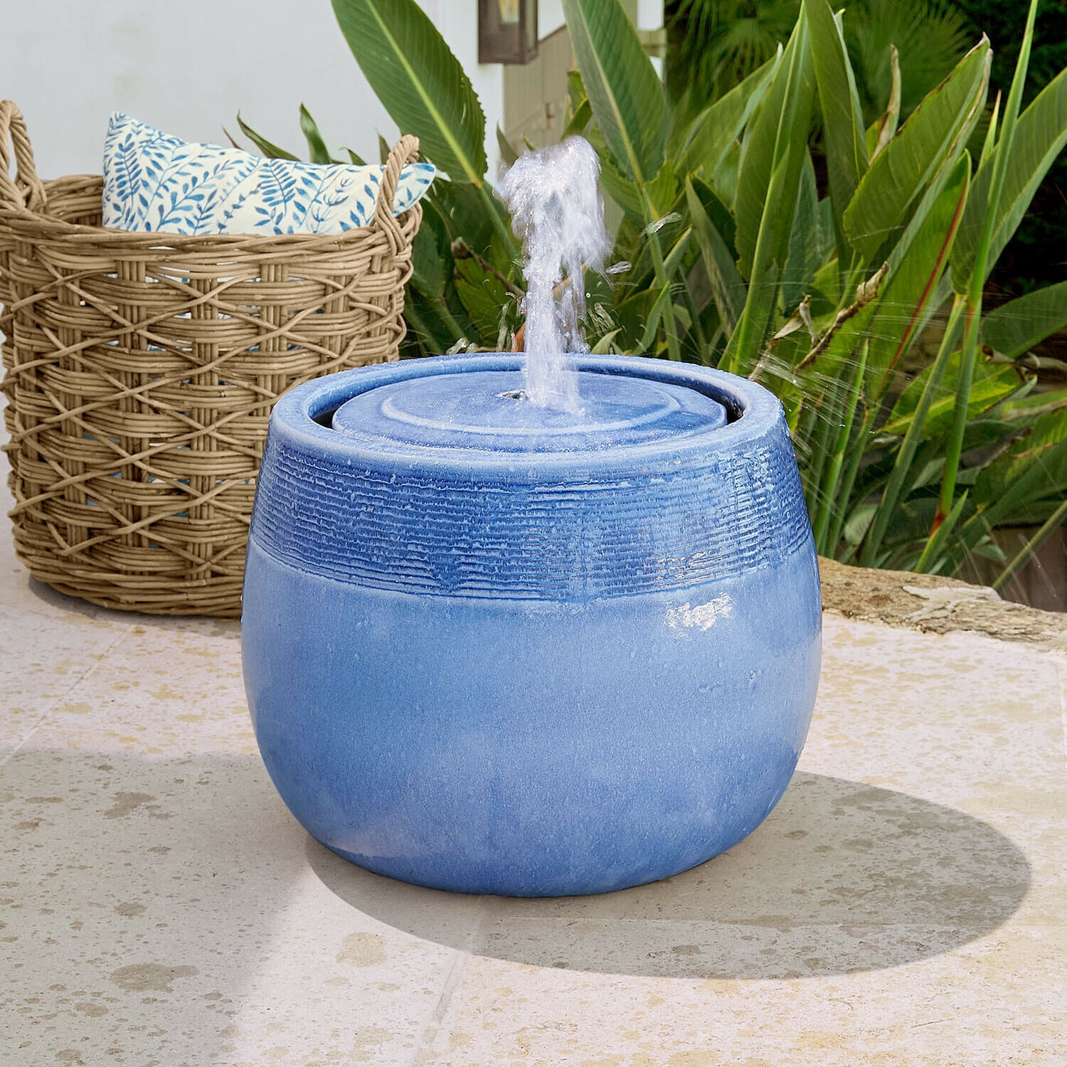 Fontaine Seravia Fontaine de jardin en céramique bleue avec jet d'eau, entourée de plantes vertes et panier en osier