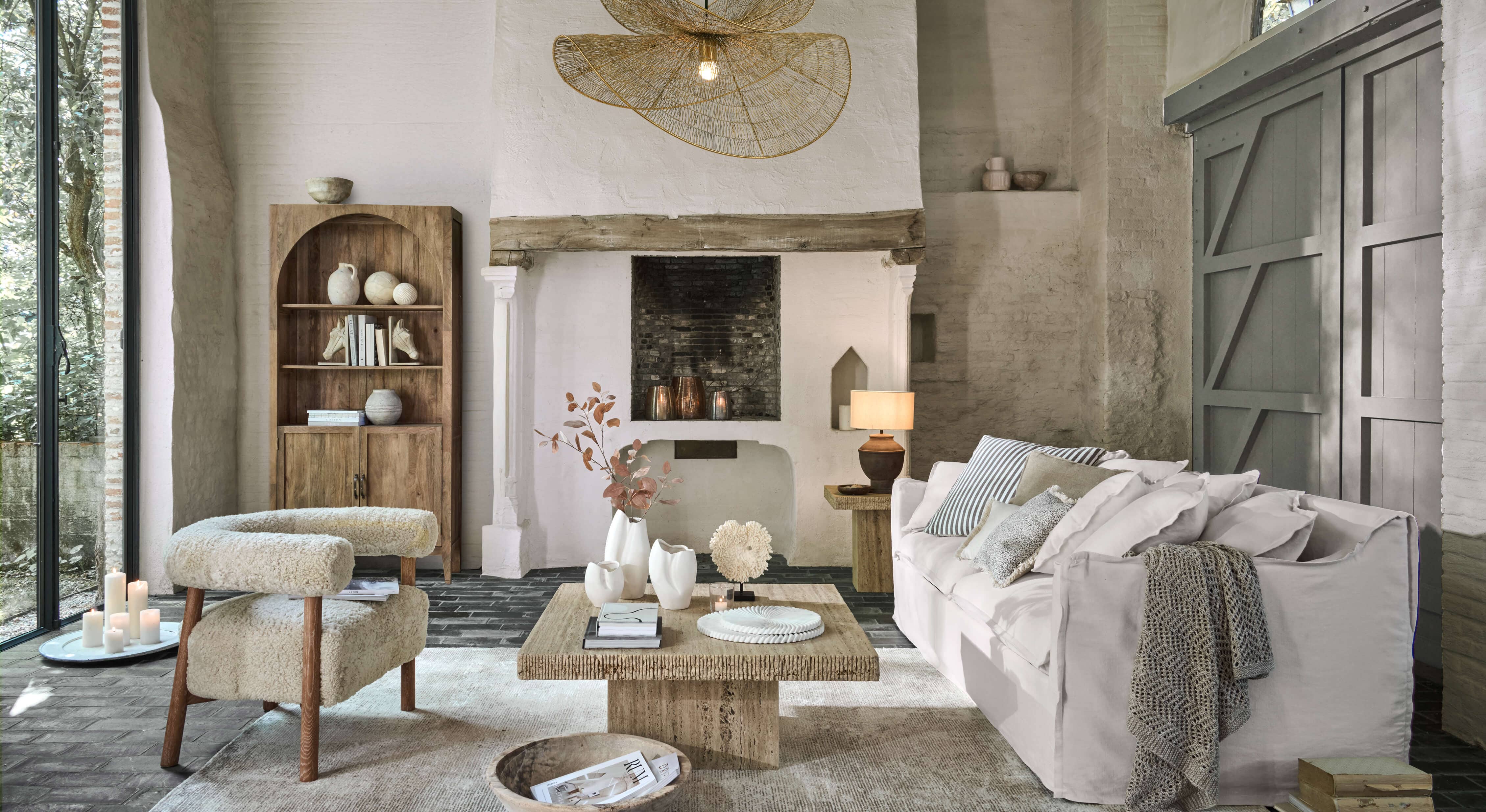 Salon chaleureux avec canapé blanc, fauteuil beige en tissu et table basse en bois sur tapis clair