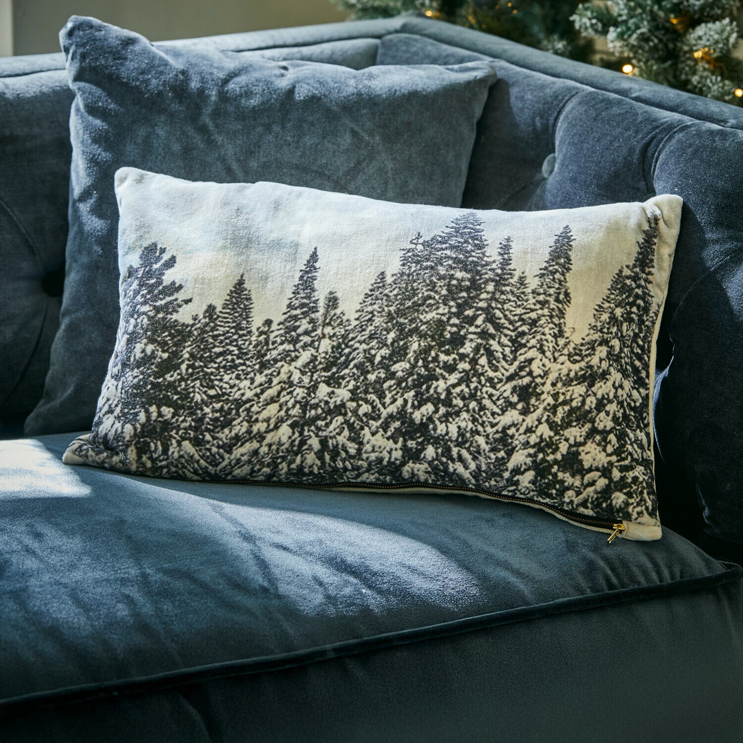 Housse de coussin Silver Creek Coussin rectangulaire décoratif avec motif forêt enneigée sur tissu clair posé sur un canapé bleu foncé