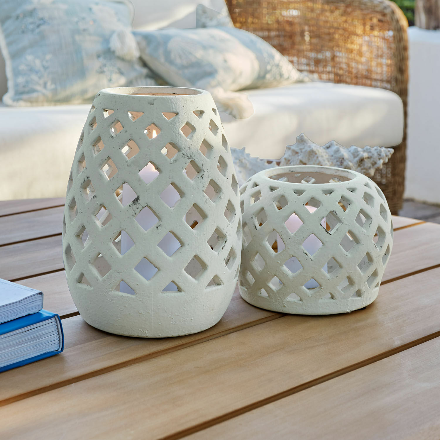 Lot de 2 photophores Serignac Deux lanternes en céramique blanche à motif ajouré posées sur une table en bois dans un salon
