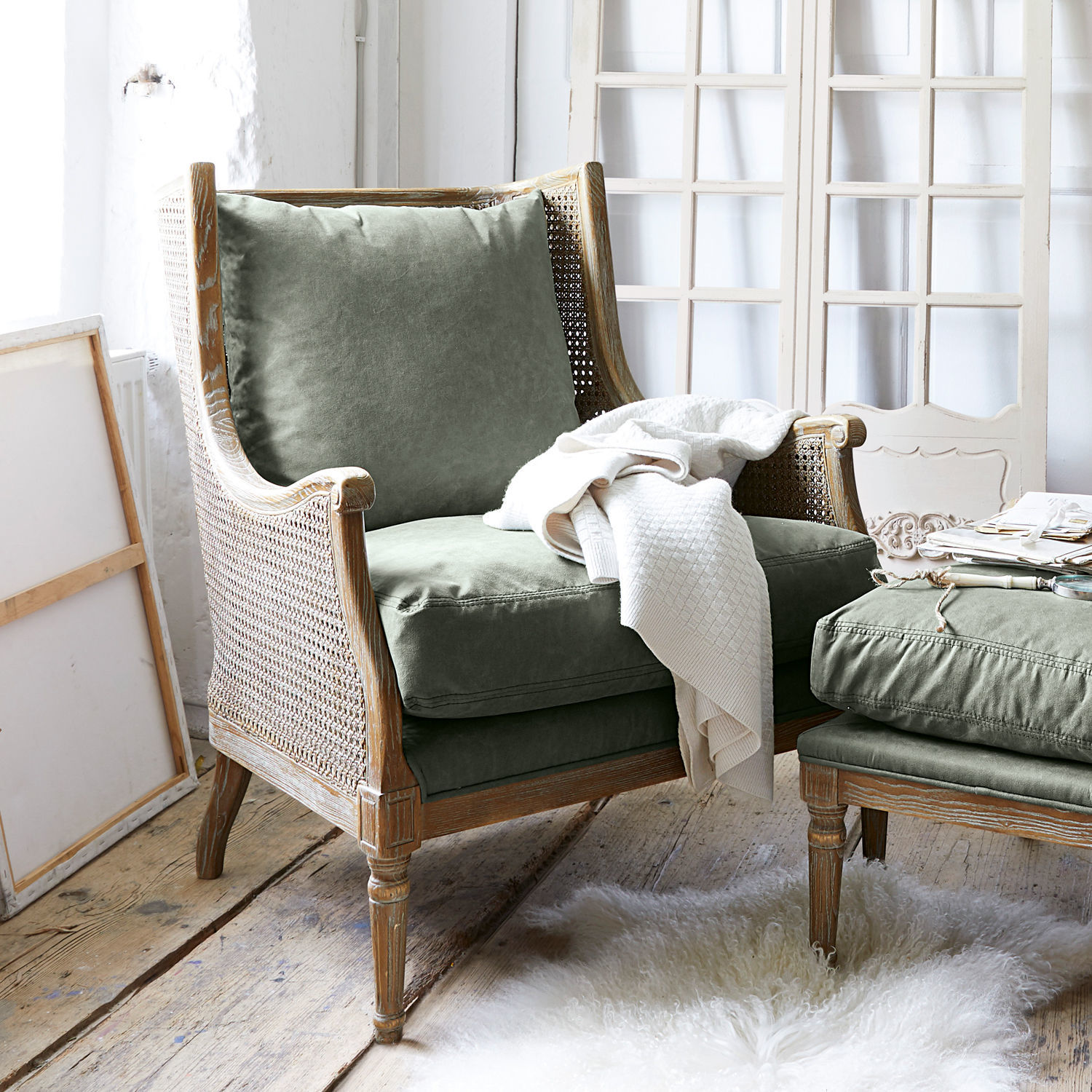 Fauteuil Greenbrier Fauteuil en bois avec coussins verts en tissu et couverture blanche sur tapis en peau d'agneau clair