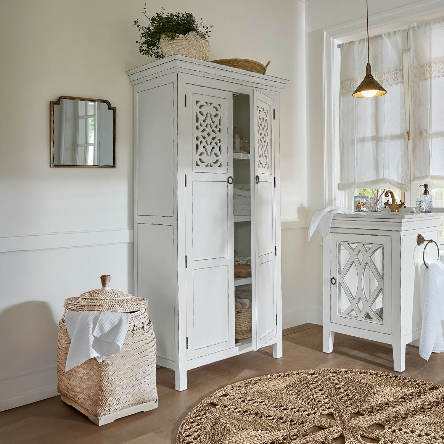 Vitrine Marvoux Armoire blanche en bois avec portes ajourées et panier en rotin tressé dans une salle de bain lumineuse