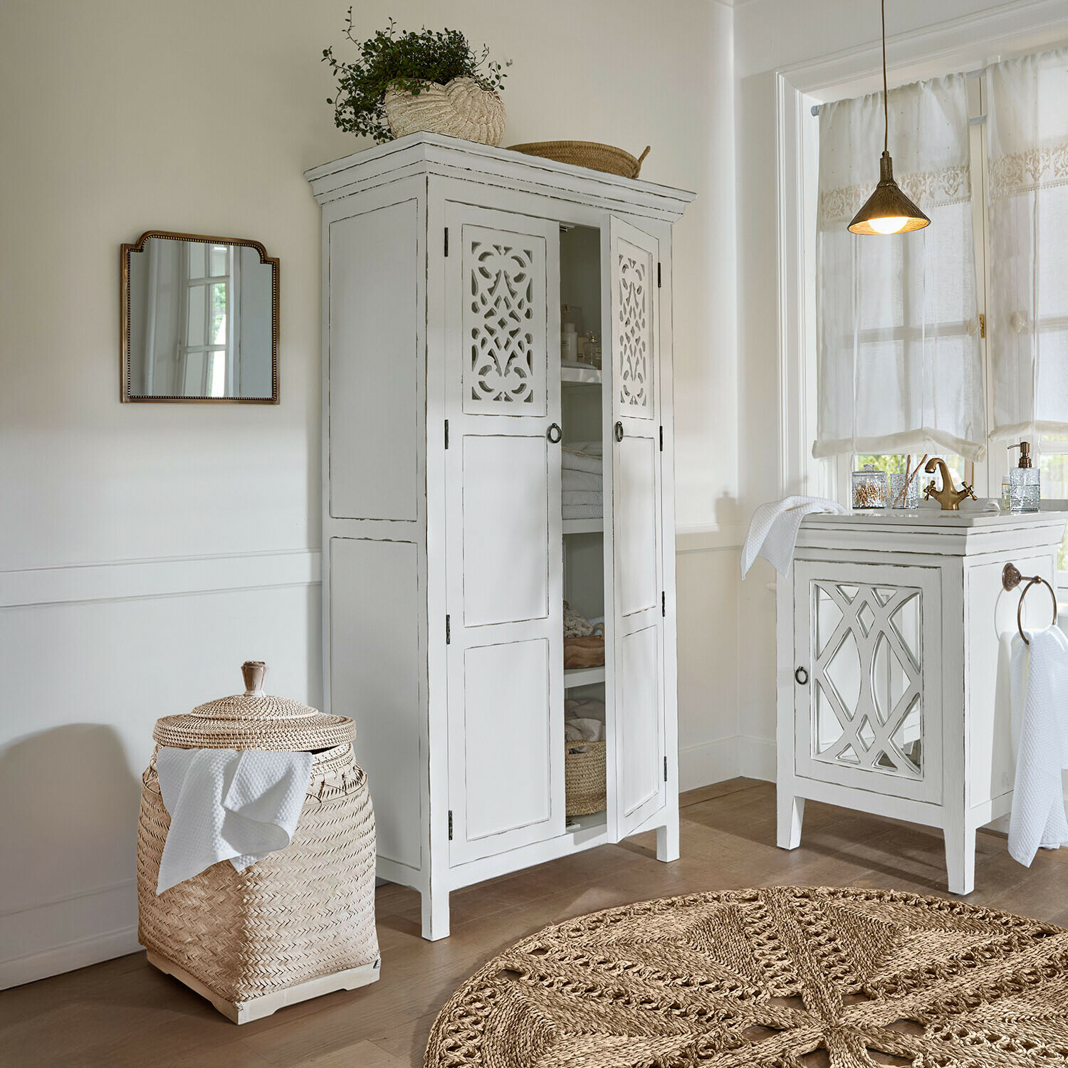 Vitrine Marvoux Armoire blanche en bois avec portes ajourées et panier en rotin tressé dans une salle de bain lumineuse