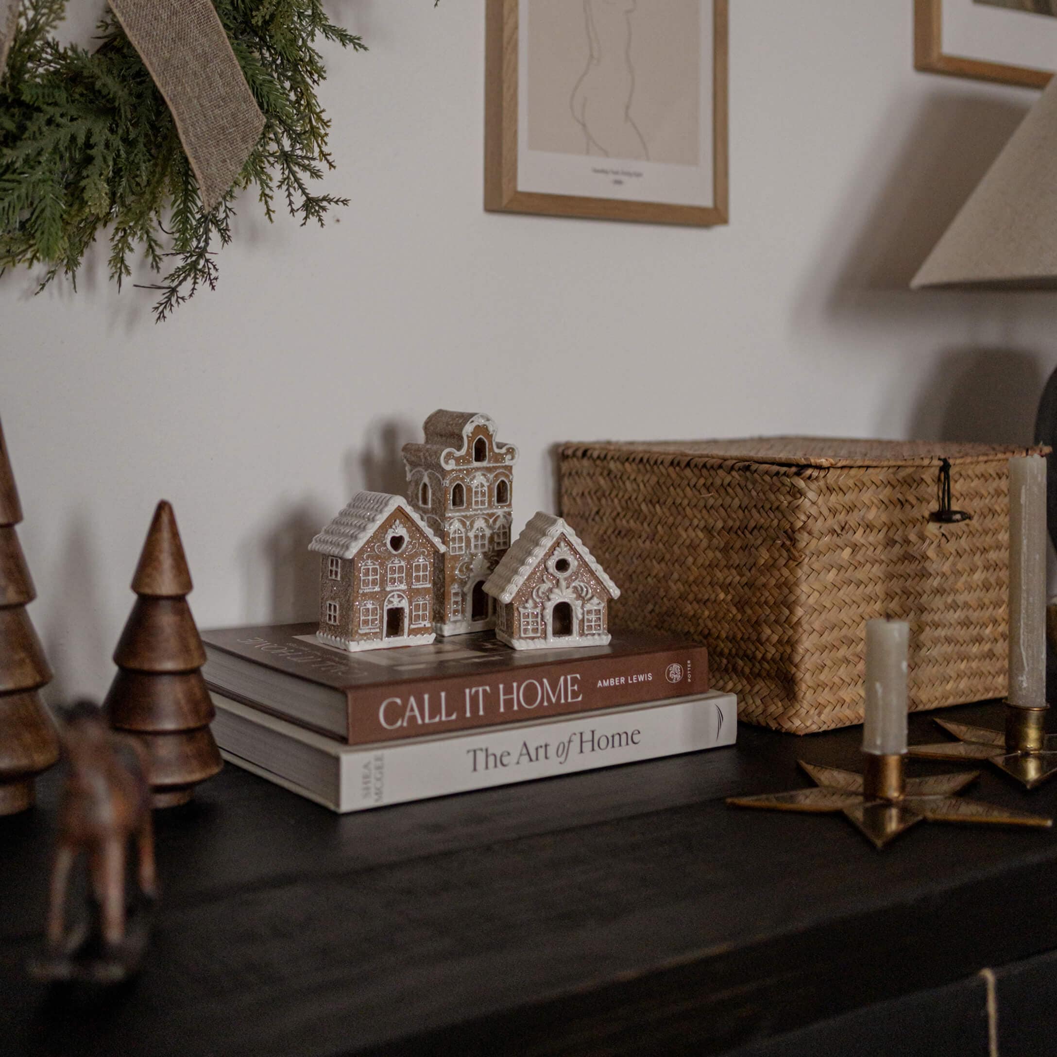 Maisons décoratives en argile sur des livres posés sur une table sombre avec bougies et éléments naturels