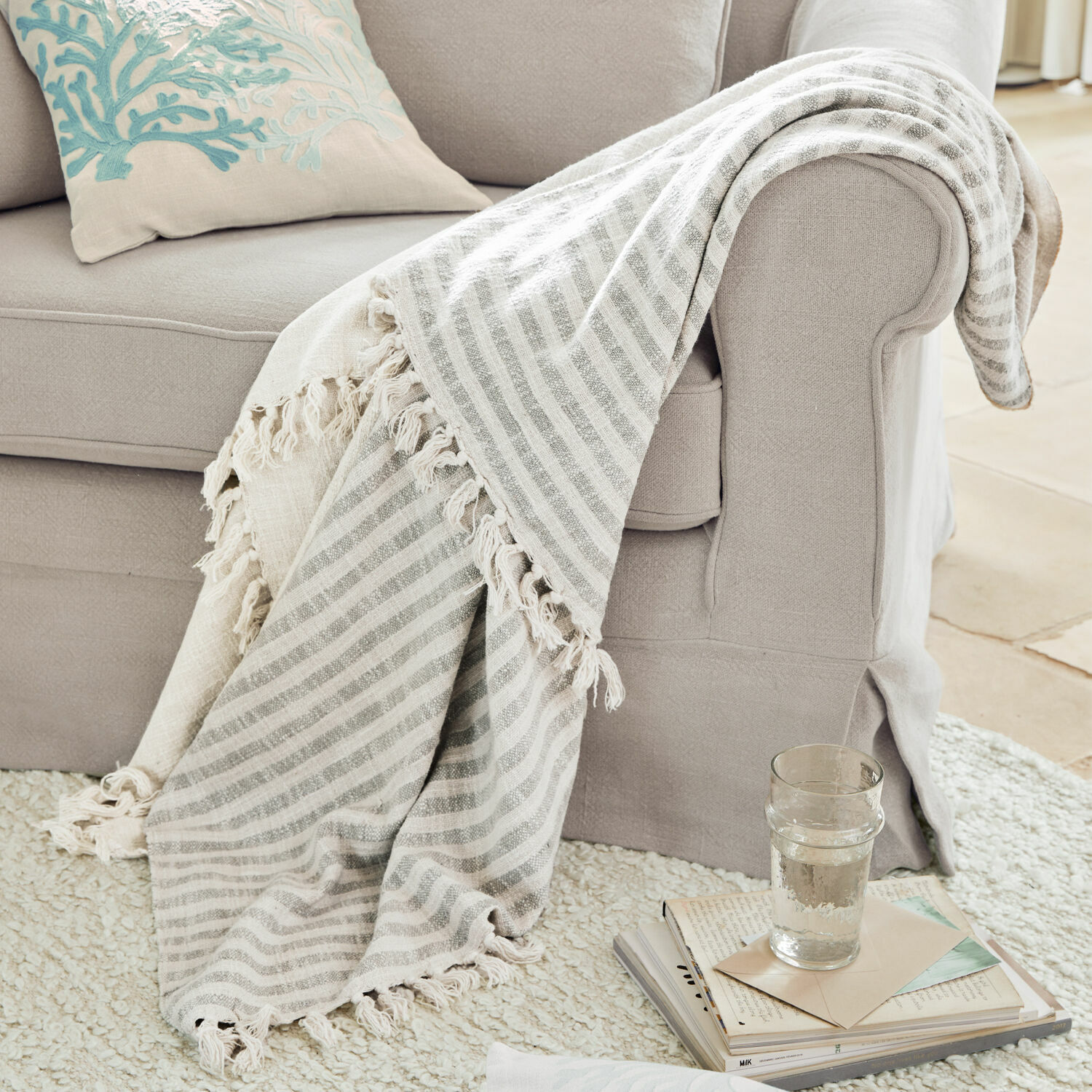 Plaid Marpent Plaid beige à rayures avec franges sur un canapé gris clair, accessoire cosy pour salon