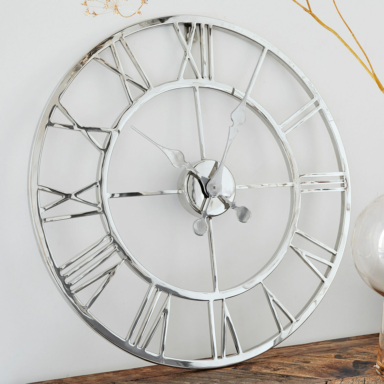 Horloge Houston Horloge murale ronde en métal argenté avec chiffres romains posée sur une table en bois