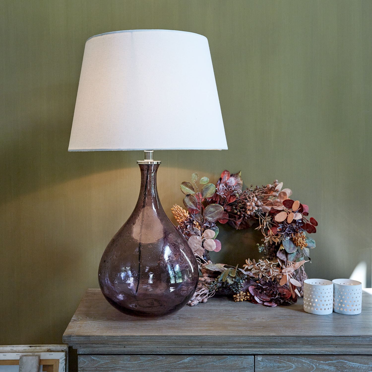 Lampe de table en verre avec abat-jour blanc et base marron translucide sur table en bois avec décoration
