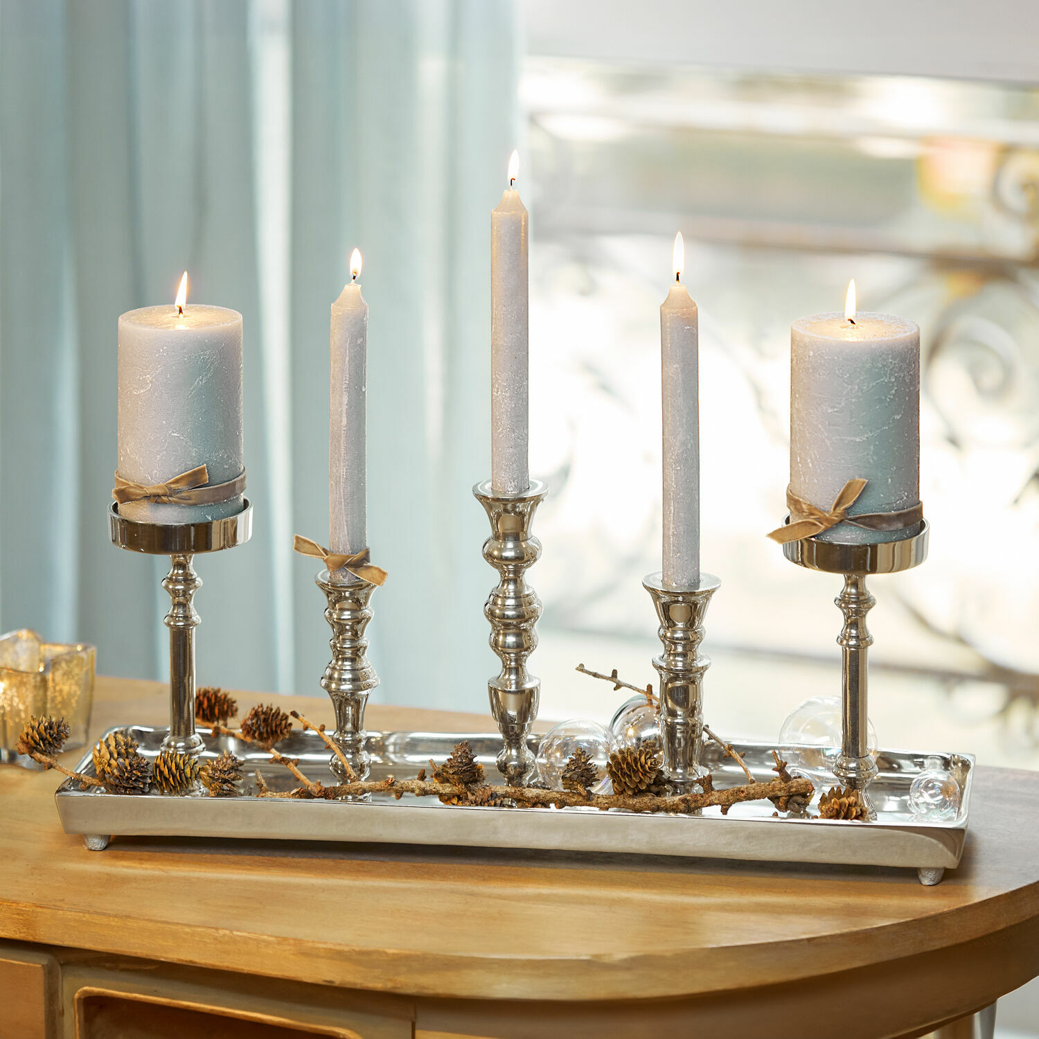 Plateau à bougies Alirra Chandelier en métal avec cinq bougies grises et décoration de pommes de pin sur table en bois