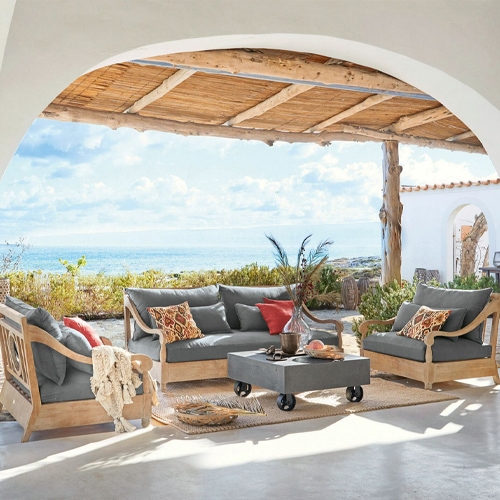 Ensemble de meubles de jardin en bois avec coussins gris sur terrasse face à la mer, mobilier détente extérieur