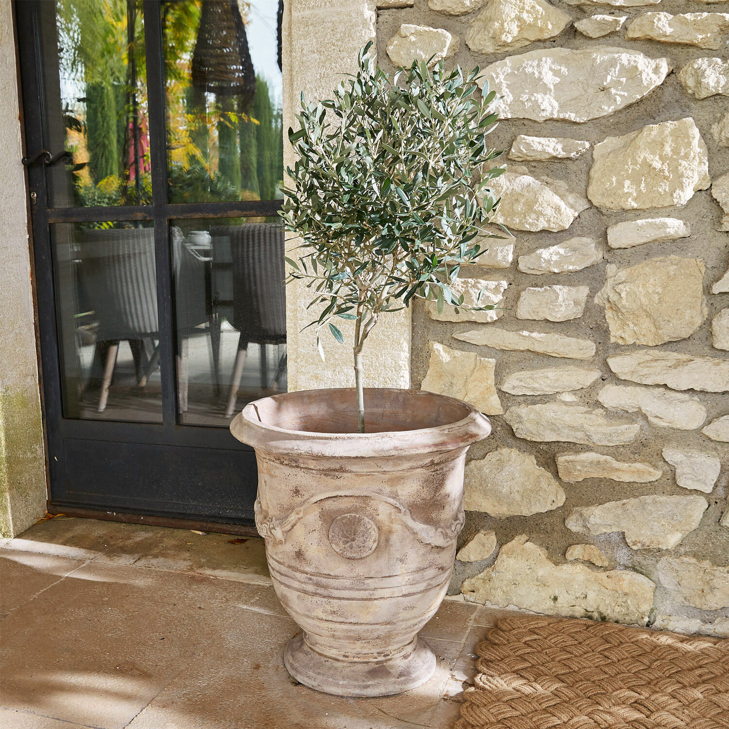 Cache-pot Garwood Grand pot décoratif en terre cuite beige avec plante verte sur terrasse en pierre
