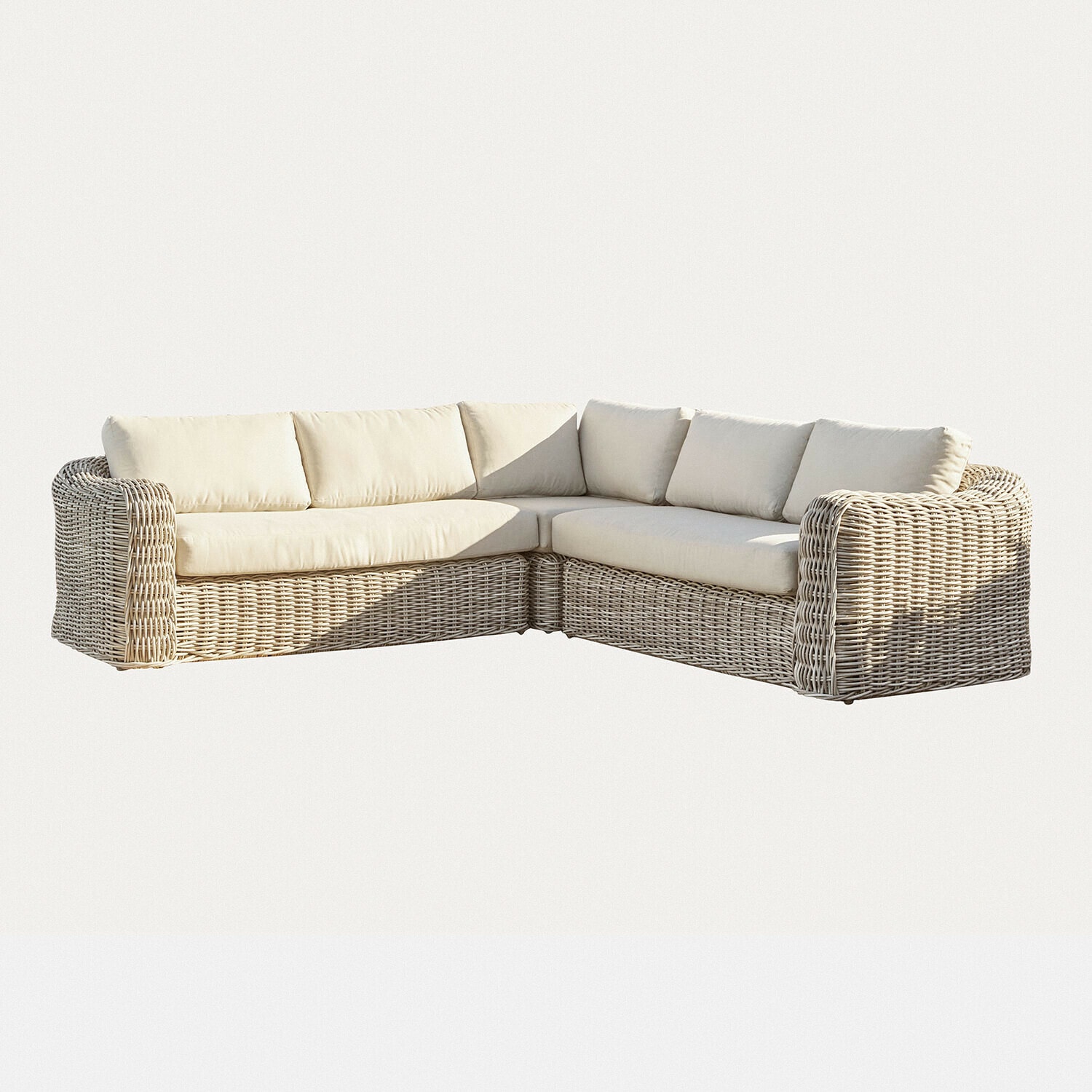 Canapé d'angle en rotin beige clair avec coussins crème, meuble confortable pour salon moderne