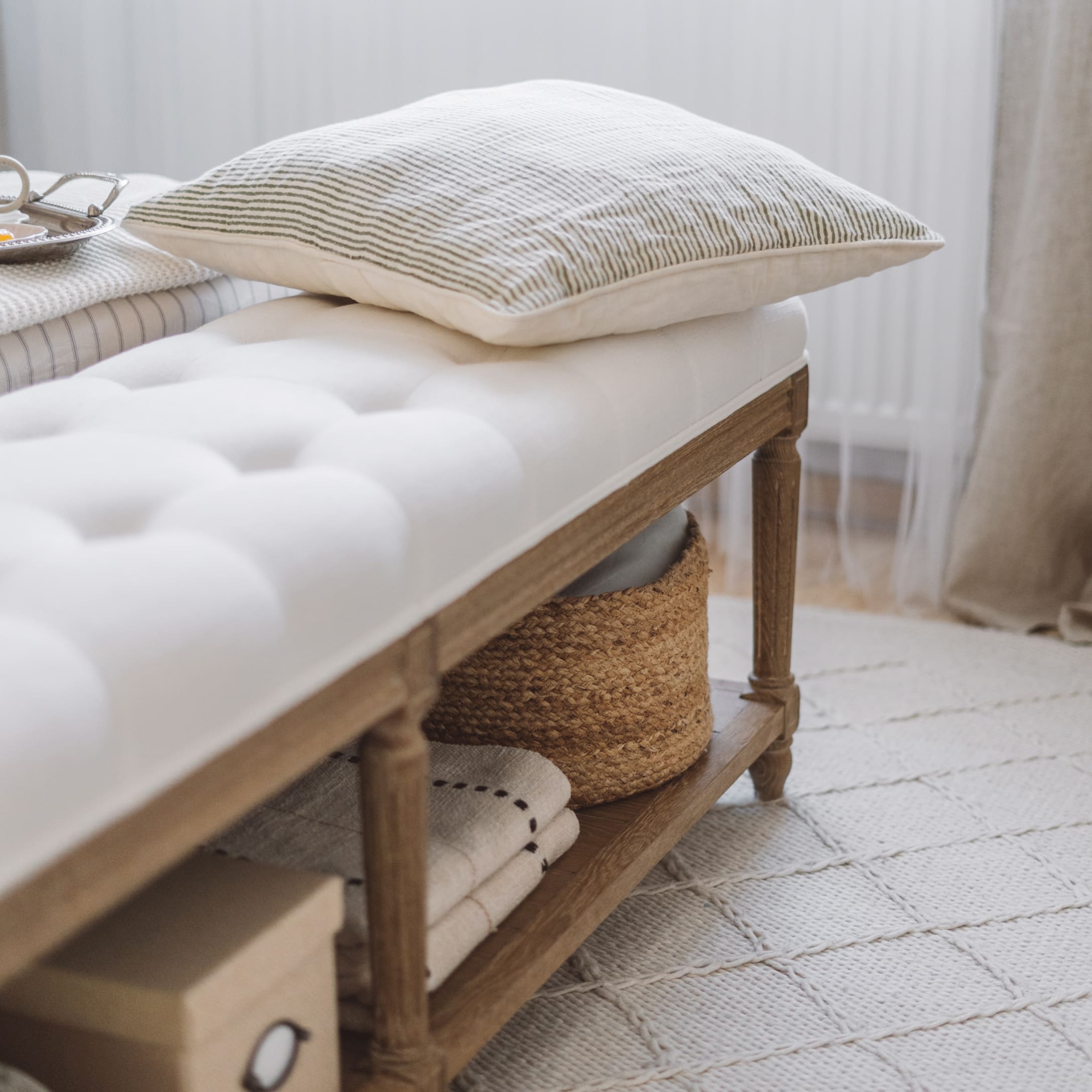 Banc en bois avec assise capitonnée blanche et coussin rayé, décoration intérieure élégante