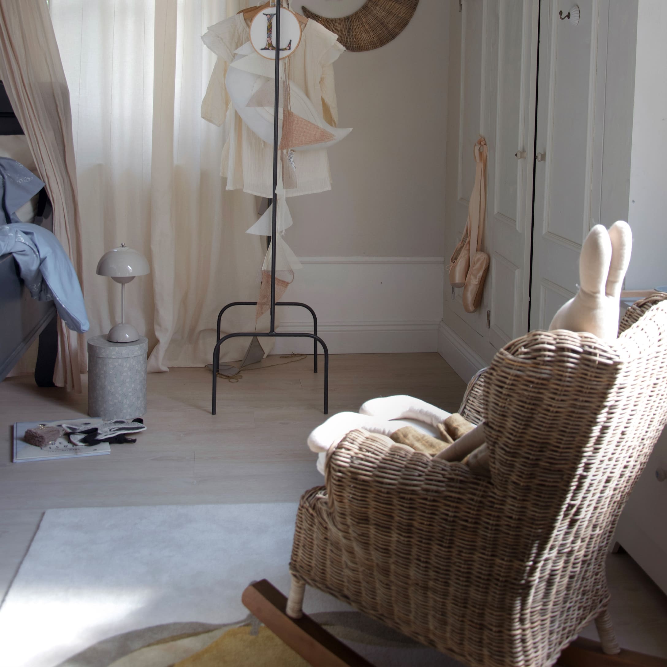 Chambre d'enfant avec fauteuil à bascule en osier et rideaux clairs, ambiance chaleureuse et décorative