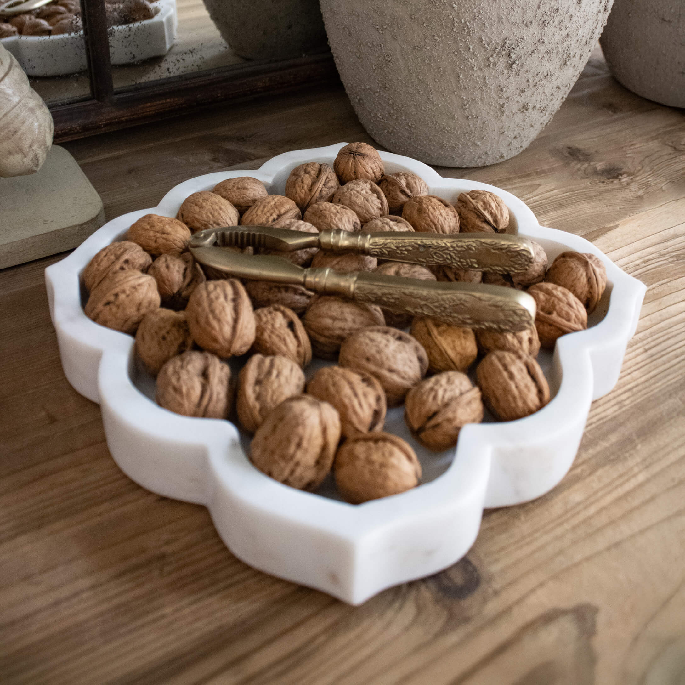 Plateau en marbre blanc avec noix et casse-noix doré sur table en bois rustique