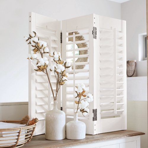 Paravent en bois blanc avec volets persiennes sur une table, décoré de fleurs de coton, style rustique