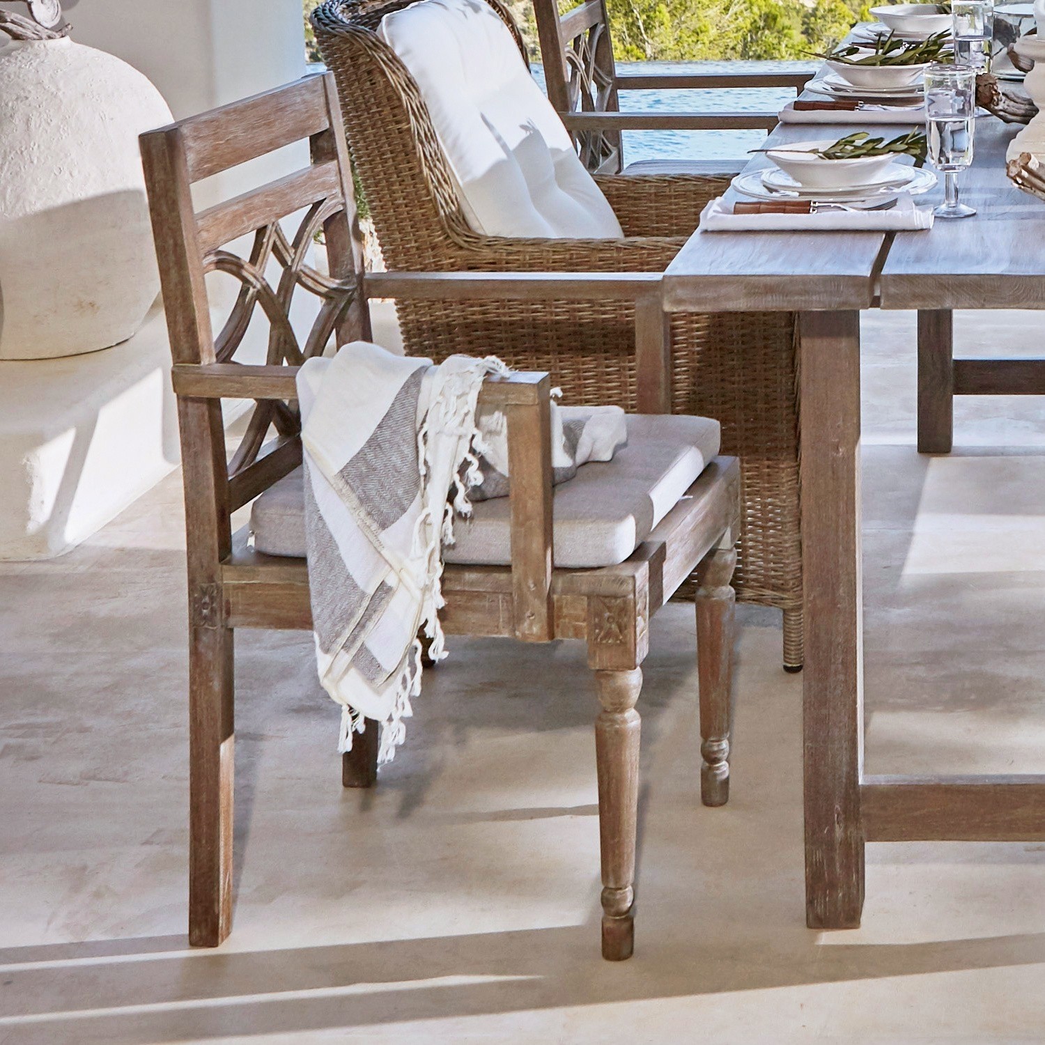 Chaise Chesterfield Chaise en bois avec coussin et plaid gris clair près d'une table rustique sur la terrasse