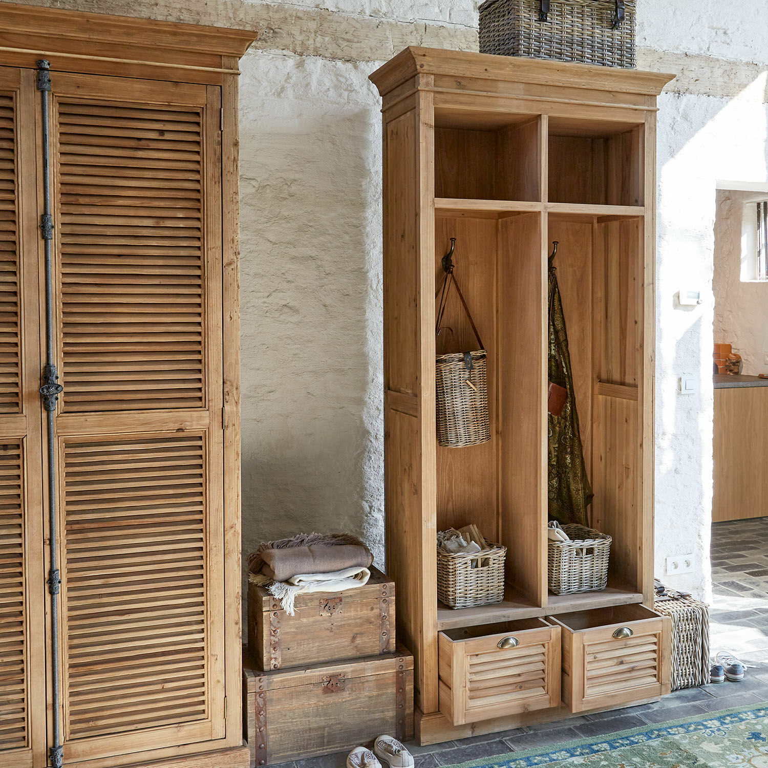 Meuble d’entrée Farnham Armoire en bois et vestiaire ouvert avec paniers et crochets dans une pièce claire aux murs en pierre