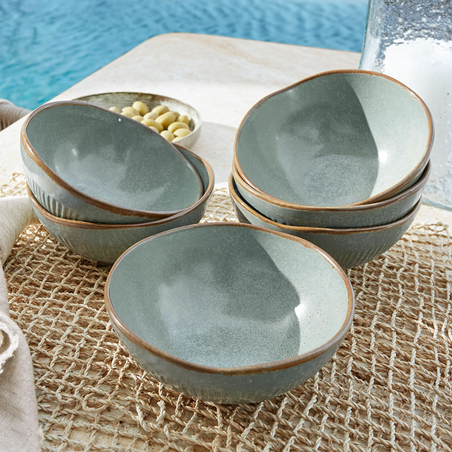 Lot de 6 bols Périers Ensemble de bols en céramique verts avec bord brun posés sur un tapis naturel sur une table extérieure