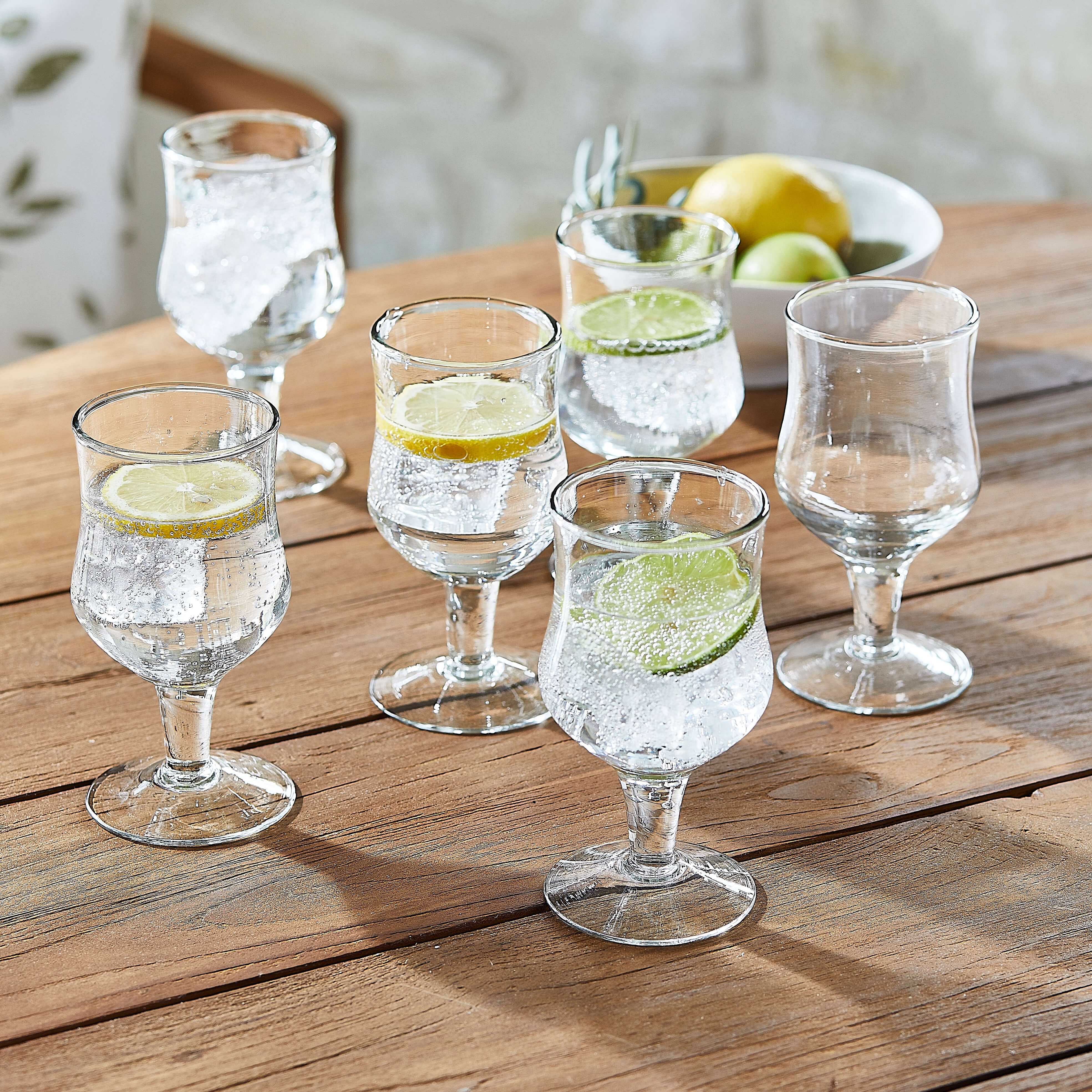 Ensemble de six verres transparents avec eau pétillante et tranches de citron et citron vert sur table en bois