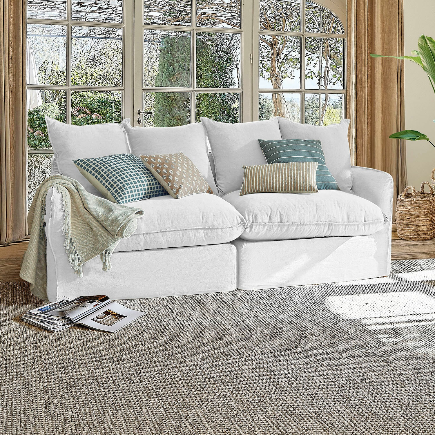 Canapé Dunswater Canapé blanc en tissu avec coussins à motifs variés dans un salon lumineux avec grandes fenêtres