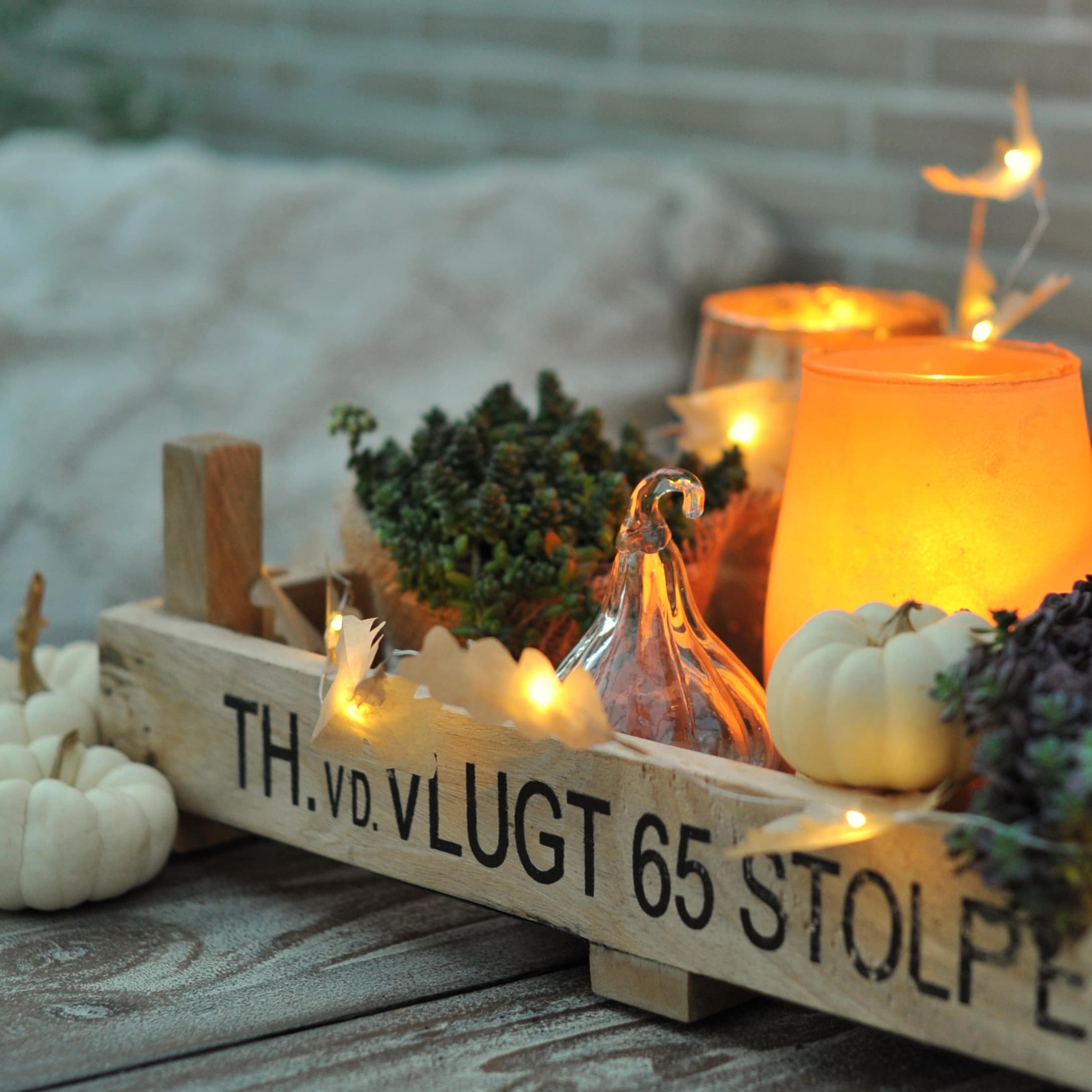 Caisse en bois avec décorations d'automne, petites citrouilles blanches et lanternes lumineuses