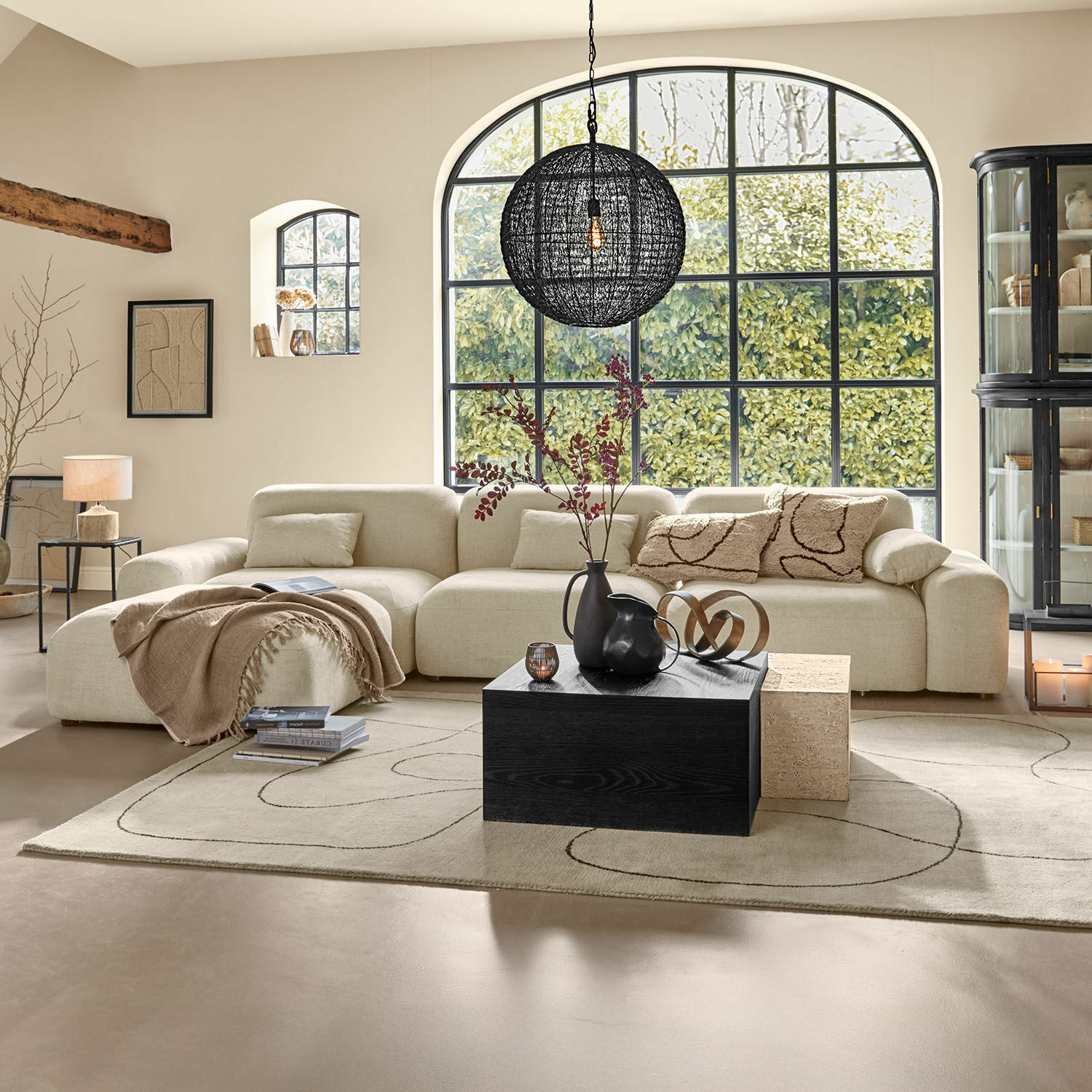 Canapé Marnivelle Canapé d'angle beige avec coussins moelleux et table basse noire dans un salon moderne lumineux