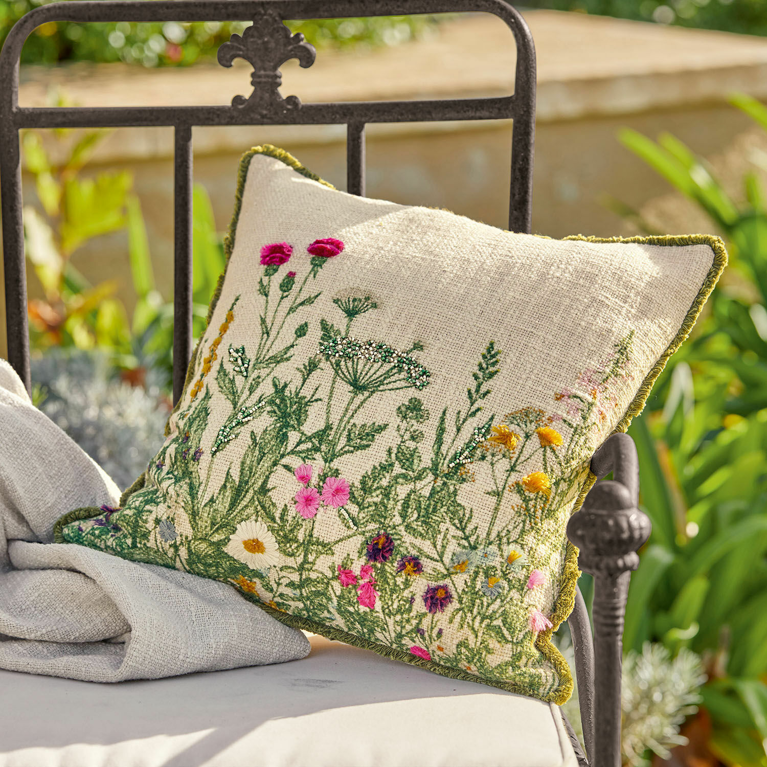 Housse de coussin Aranno Coussin en lin beige avec broderie florale colorée et bordure verte sur chaise de jardin en métal
