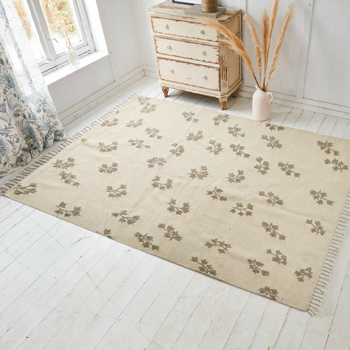 Tapis beige à motif floral avec franges, matériau doux, décoration de sol dans une pièce lumineuse