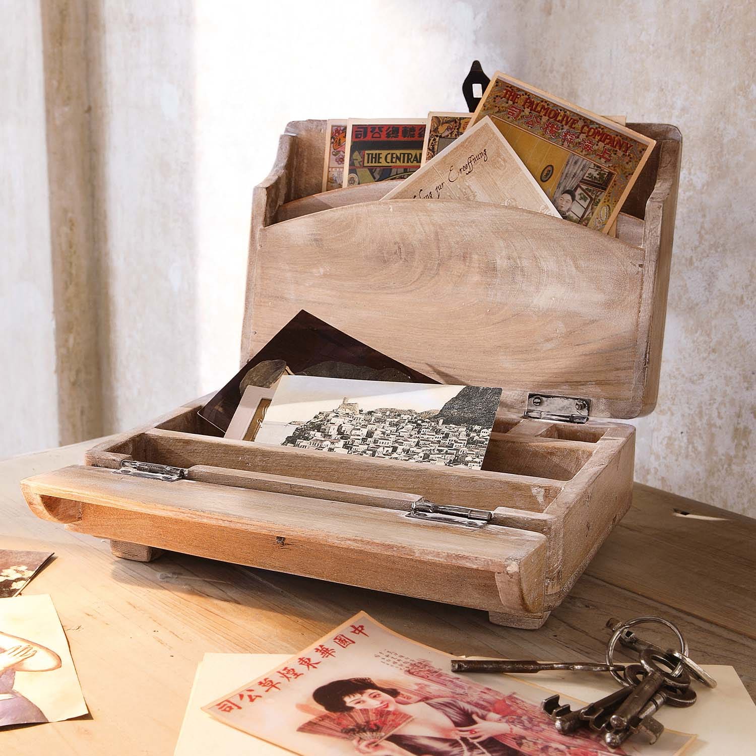 Boîte en bois naturel pour lettres avec cartes postales vintage et clés métalliques sur table en bois