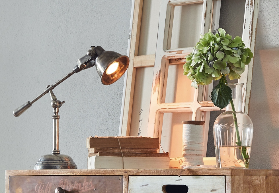 Lampe de bureau en métal style industriel sur meuble en bois avec livres et vase à fleur verte
