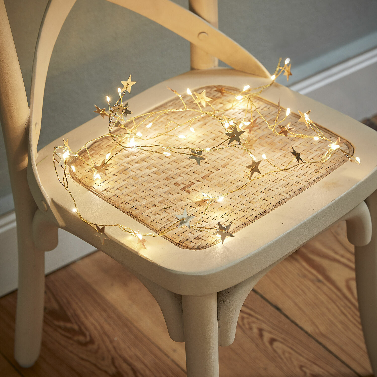Guirlande lumineuse Vernham Guirlande lumineuse étoilée à lumière chaude posée sur une chaise en osier clair