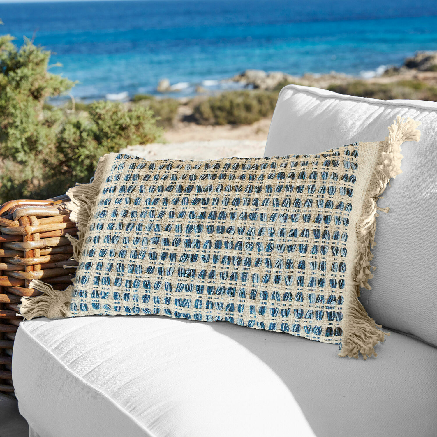 Housse de coussin Monrovie Coussin décoratif en coton beige et bleu à carreaux avec franges sur canapé blanc en extérieur