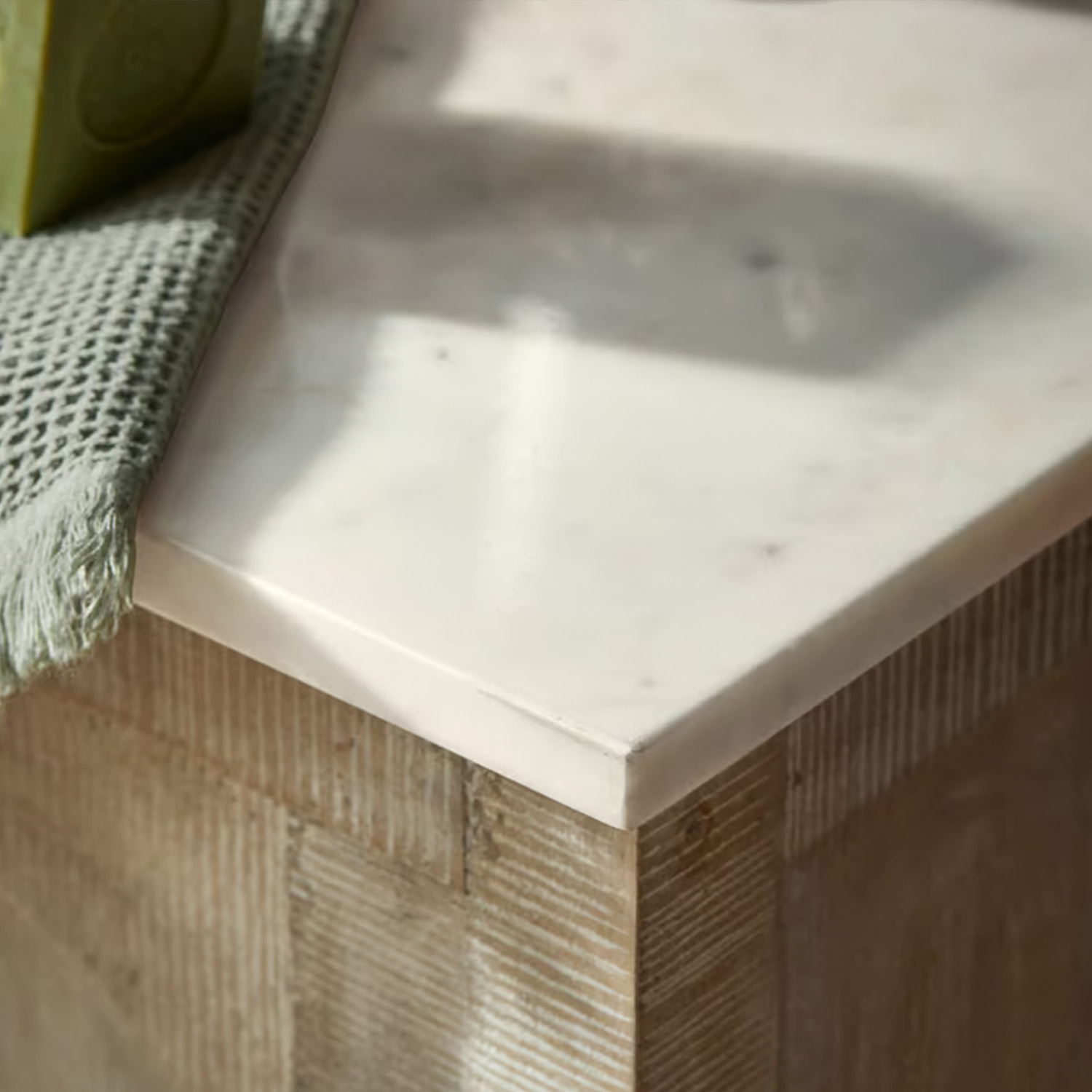 Plan de travail en marbre blanc sur base en bois avec serviette verte en tissu, meuble moderne