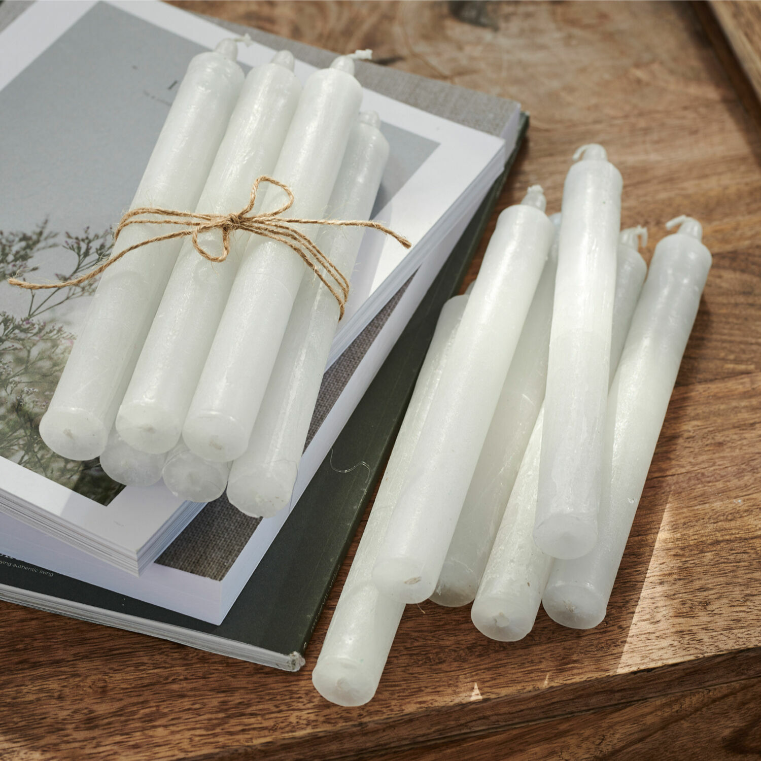 Lot de 12 bougies Bauceau Lot de bougies blanches en cire sur une table en bois avec des livres, décoration intérieure