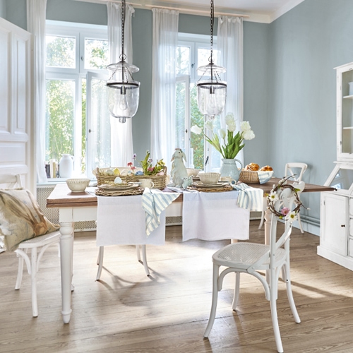 Salle à manger rustique avec table et chaises blanches en bois, décorations pastel lumineuses