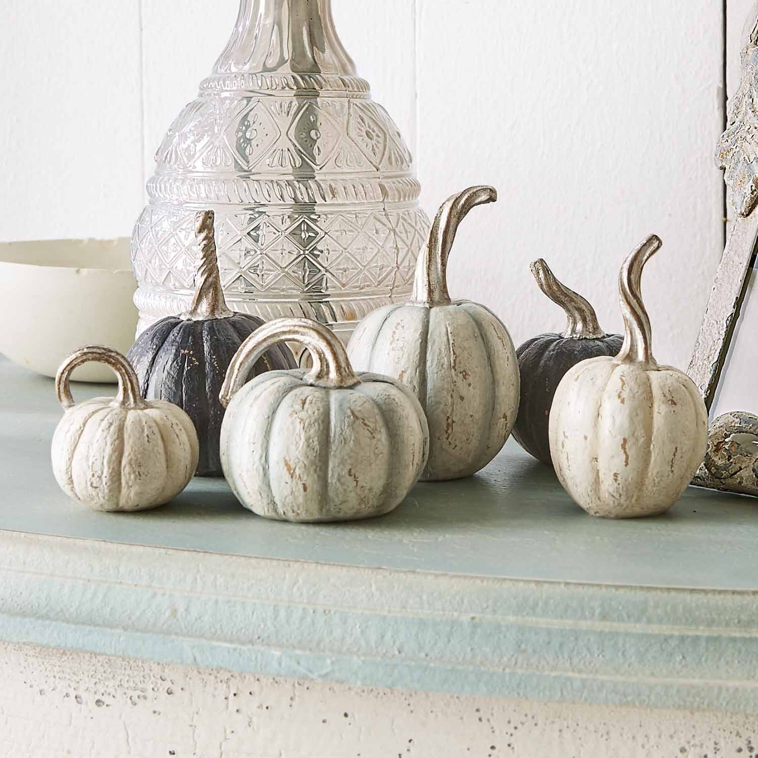 Citrouilles décoratives en métal blanc et noir posées sur une étagère claire pour décoration automnale